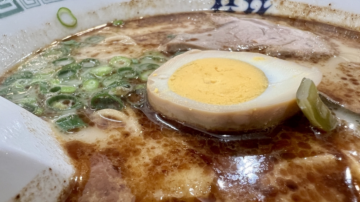 桂花拉面汤面上漂浮的半熟味玉和青葱特写