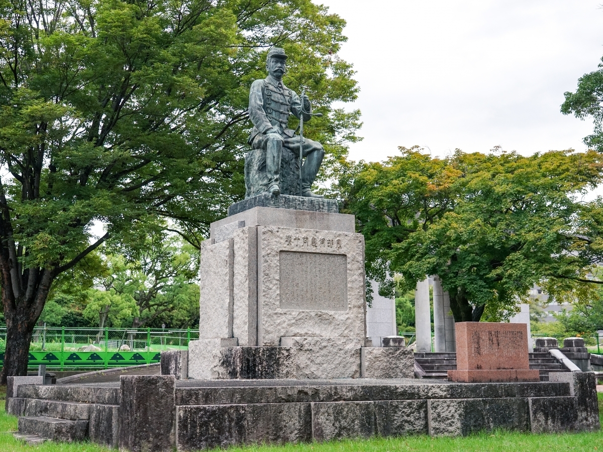 身穿军服、手扶佩剑端坐的谷干城像及台座铭文全景