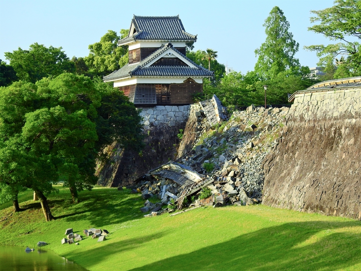 무너진 석축과 지붕재가 남아있는 비탈 위에 서 있는 구마모토성의 망루
