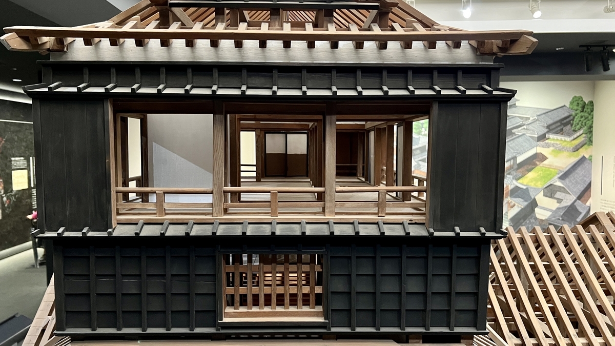 목조 들보와 툇마루가 보이는 구마모토성 천수각 모형의 한 방을 정면에서 포착한 전시