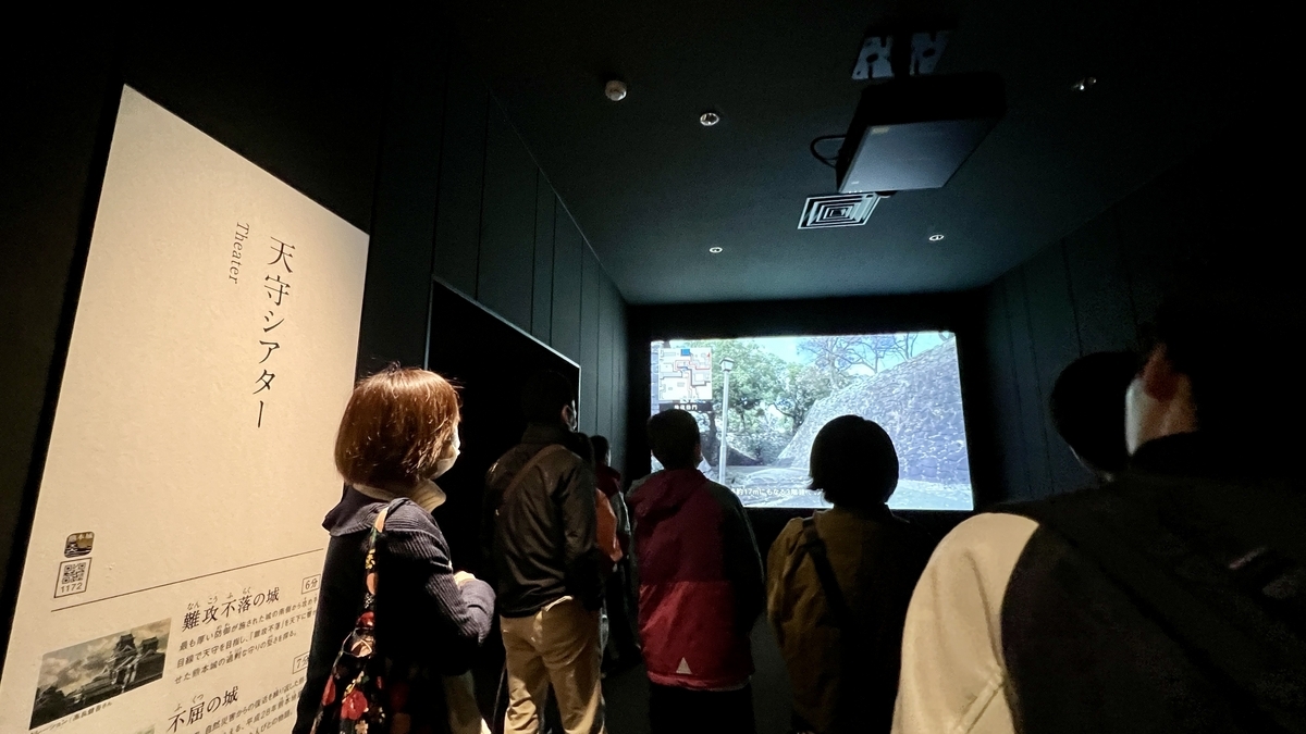 천수 시어터의 어두운 실내에서 석축 영상을 감상하는 방문객들의 뒷모습