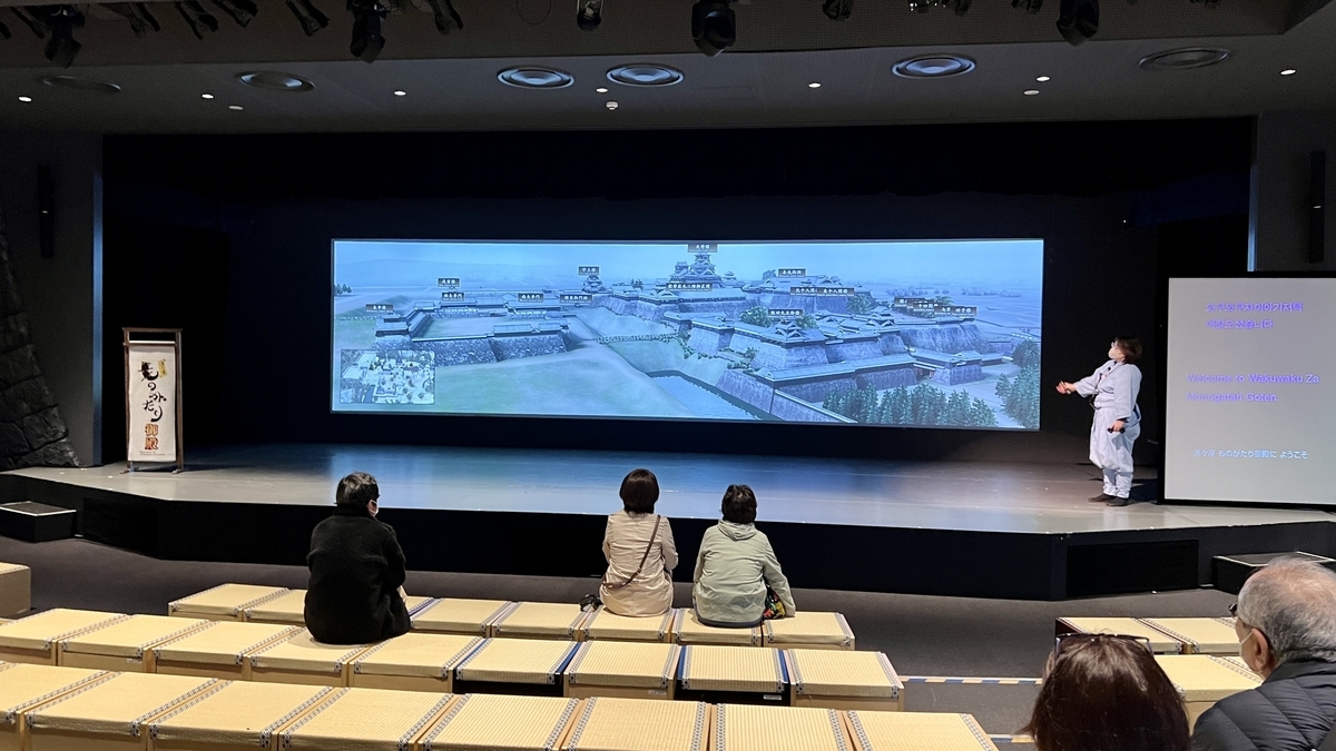 구마모토성 복원 영상을 대형 스크린에서 상영하며 직원이 해설하는 극장