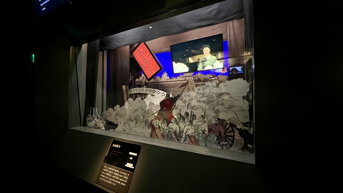 세이난 전쟁 그림연극 스타일의 종이 오리기 전시와 뒤편의 영상 스크린