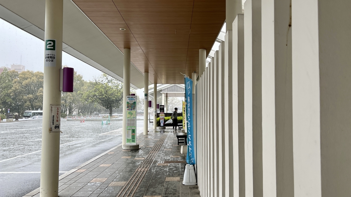 지붕이 있는 대기 공간과 비에 젖은 노면이 있는 사쿠라노바바 성채원 버스 정류장