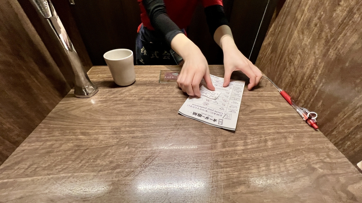 칸막이 좌석에서 직원에게 주문 용지를 건네 주문 완료