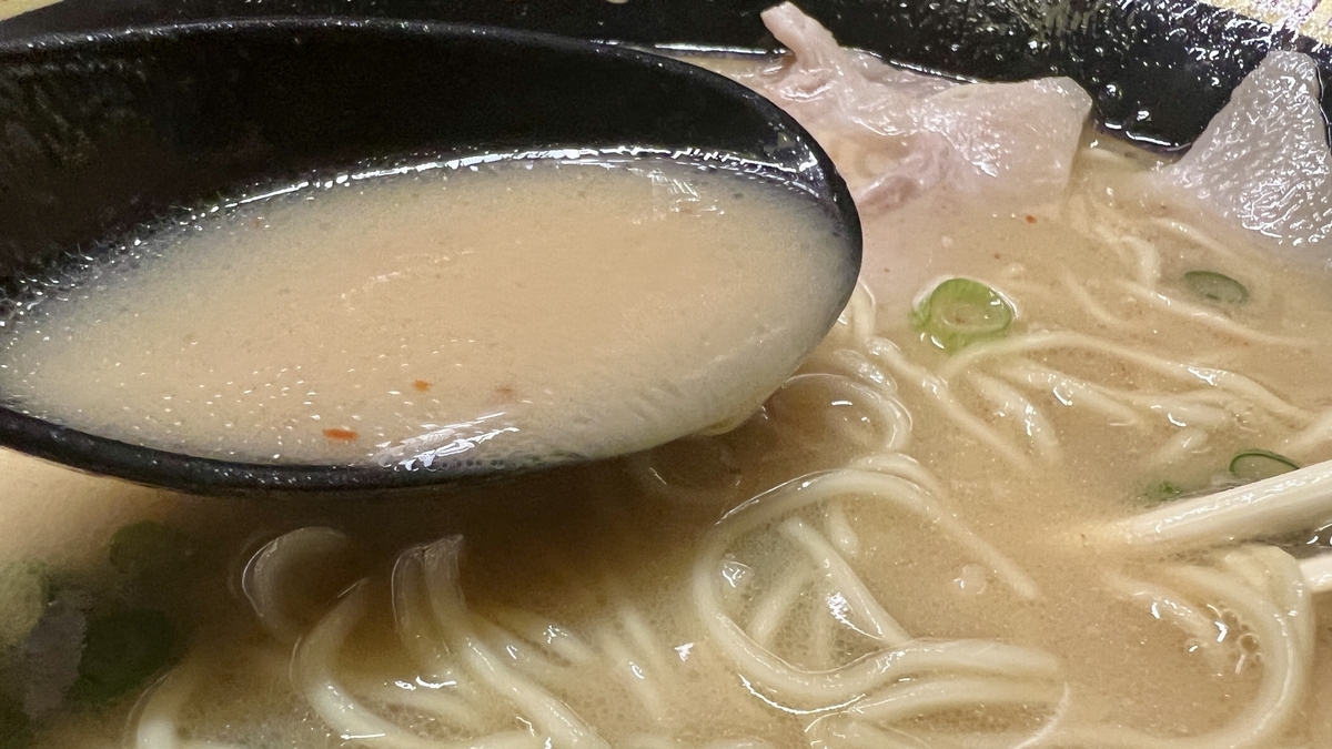 국자로 떠낸 이치란의 진한 돈코츠 국물과 가는 면 클로즈업