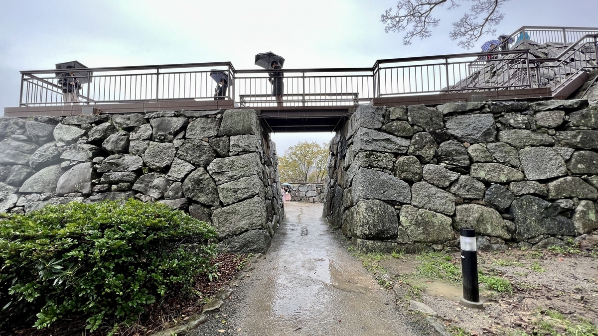 橫跨石牆切口上方的天守台觀景台和雨中的通道