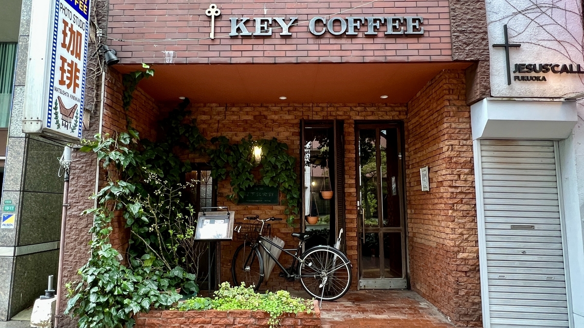담쟁이덩굴이 감긴 붉은 벽돌 벽의 마쓰시타 기념관 입구와 KEY COFFEE 간판, 주차된 자전거