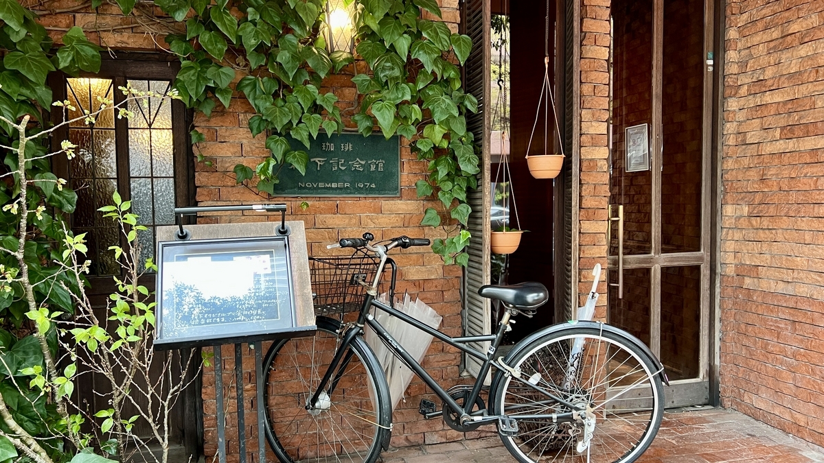 담쟁이덩굴로 덮인 벽과 안내판 앞에 자전거가 세워진 마쓰시타 기념관 입구