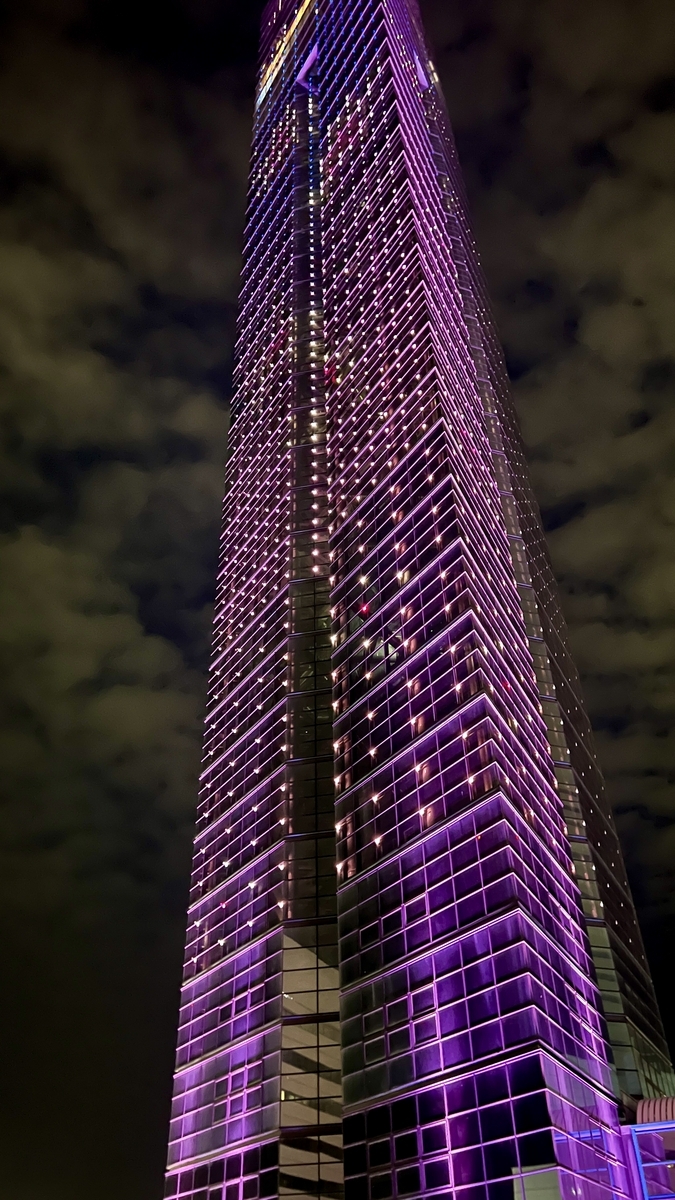 Looking up at Fukuoka Tower lit in purple, glass panels gleaming from the base