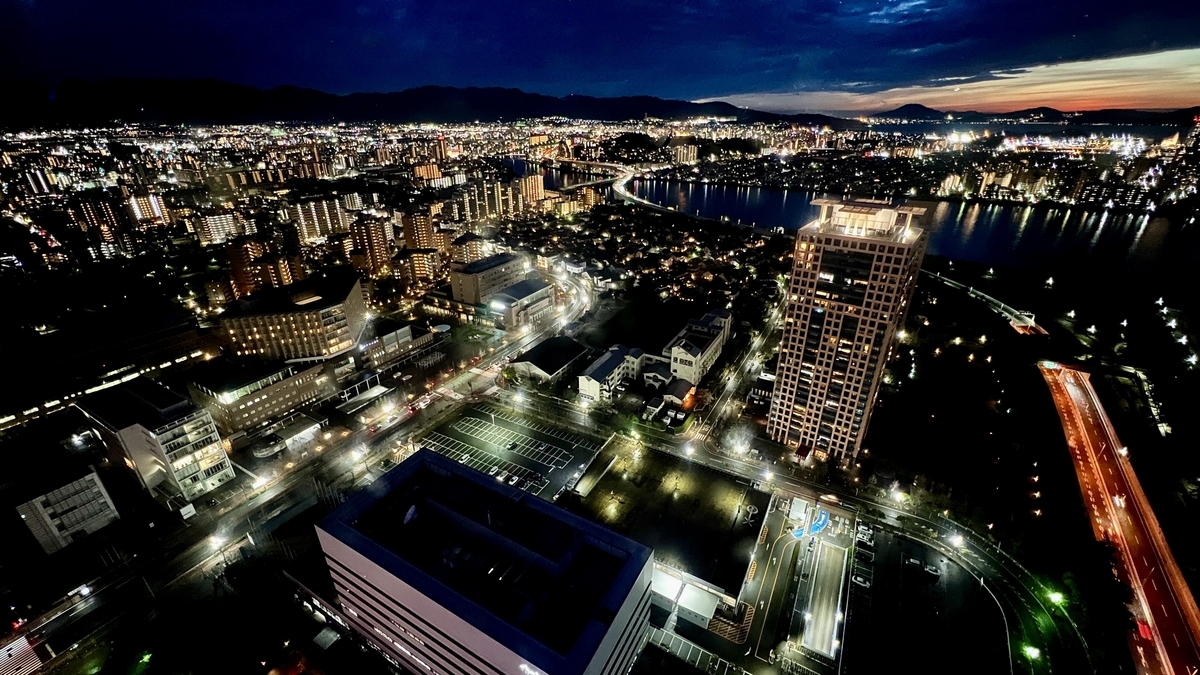 Panoramic night view of Fukuoka city lights and road light trails along the bay