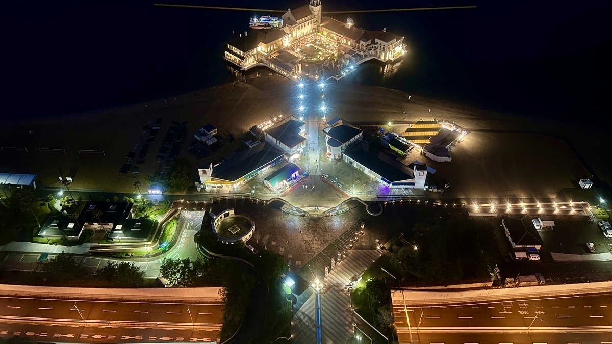 Looking down at illuminated Marizon complex with road light trails in the foreground
