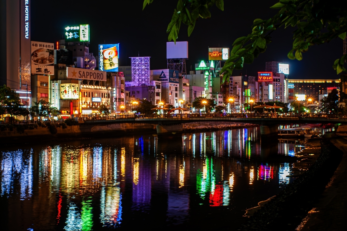Vista nocturna de Nakasu con luces de neon de los puestos callejeros reflejandose en el rio