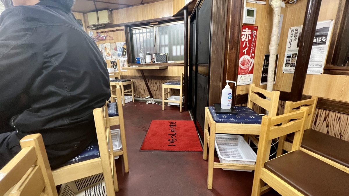 Area de mesas con sillas de madera y alfombra roja de entrada visible en el pasillo