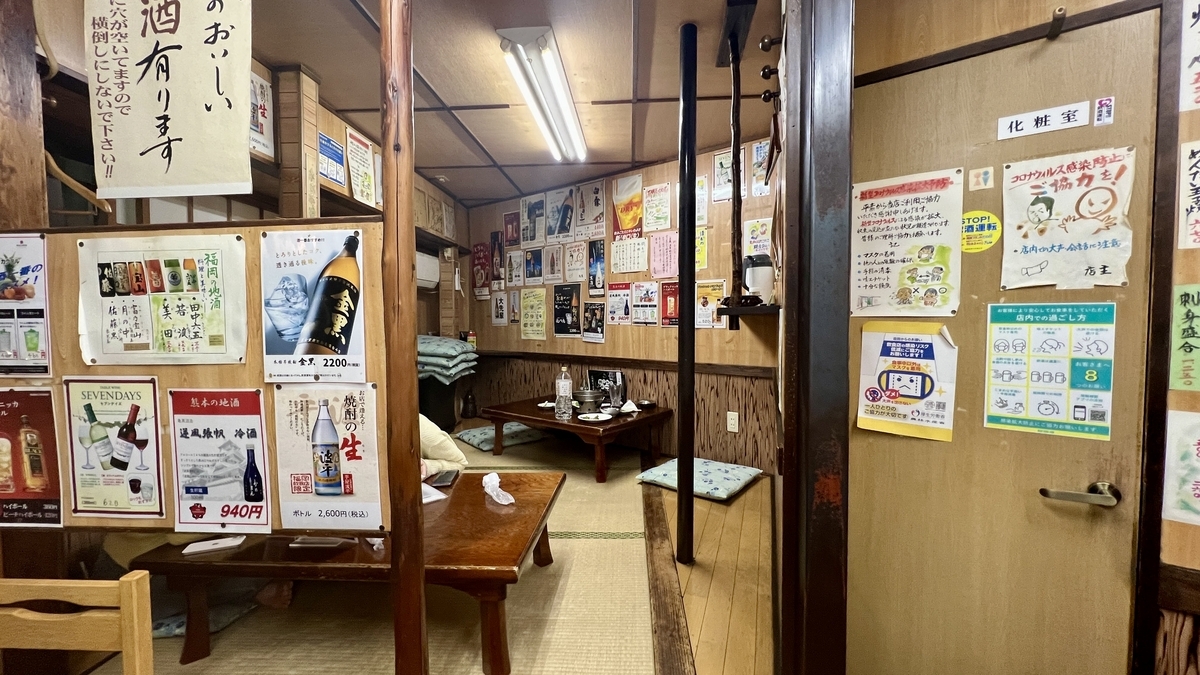 Area de asientos de tatami en la parte trasera con carteles en la pared y mesas bajas