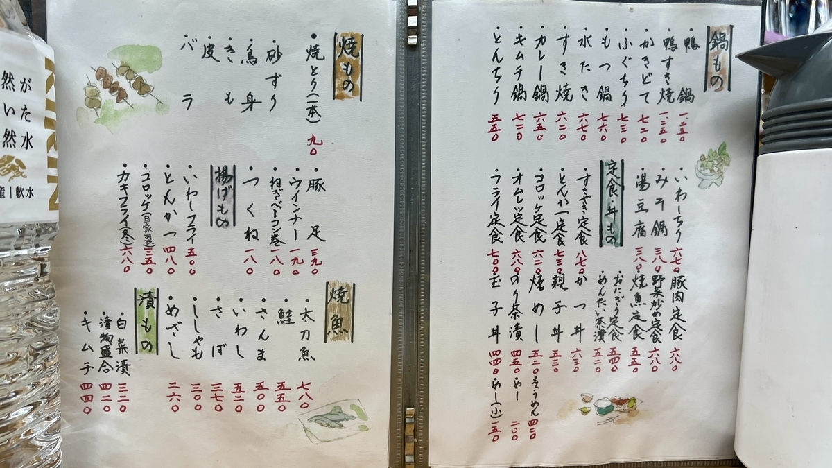 Menu abierto mostrando yakitori, pescado a la parrilla y opciones de olla caliente escritos a mano