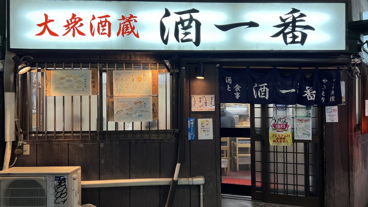 Exterior nocturno de Taishu Sakagura Sake Ichiban con prominente letrero blanco y noren