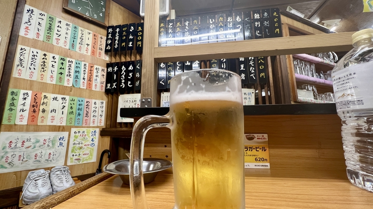 Jarra de cerveza de barril en la barra con pared de tiras de menu escritas a mano de fondo