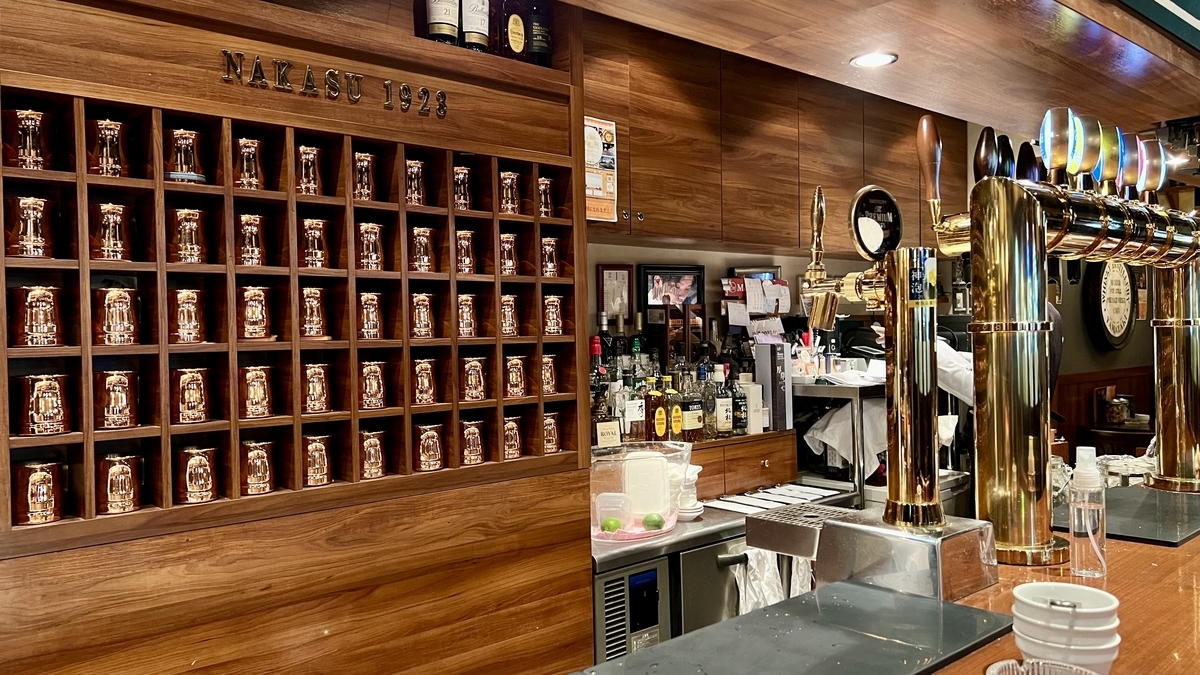 壁一面に銅製マグが並ぶカウンターとハイボール用ディスペンサー