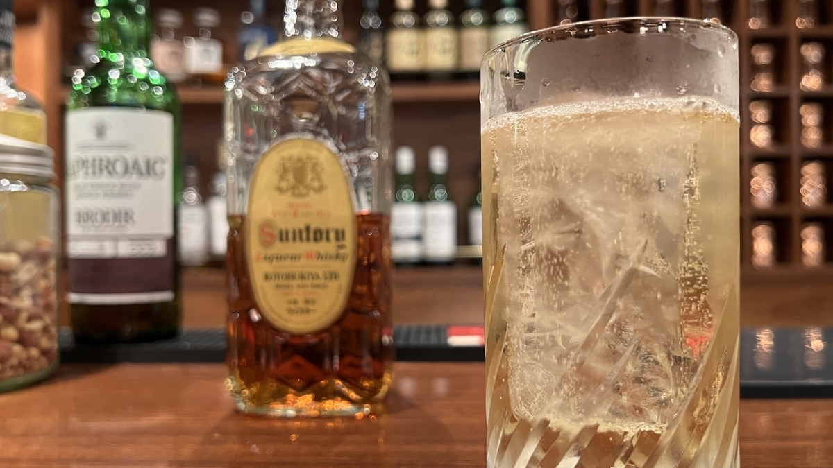 氷が入ったハイボールのグラスと背景に並ぶウイスキーボトル