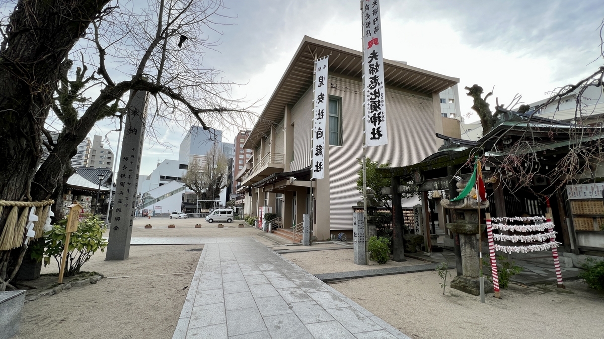 櫛田神社の境内に立つ奉納柱と絵馬掛けのある石畳通路