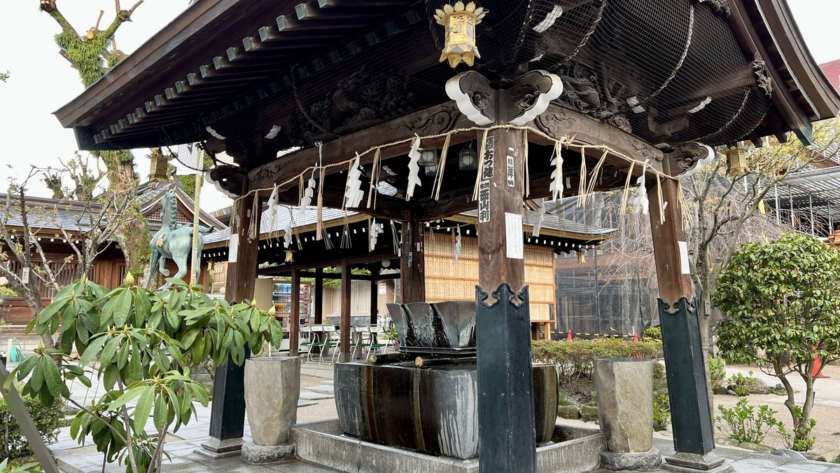 彫刻が施された屋根の手水舎と石の水盤