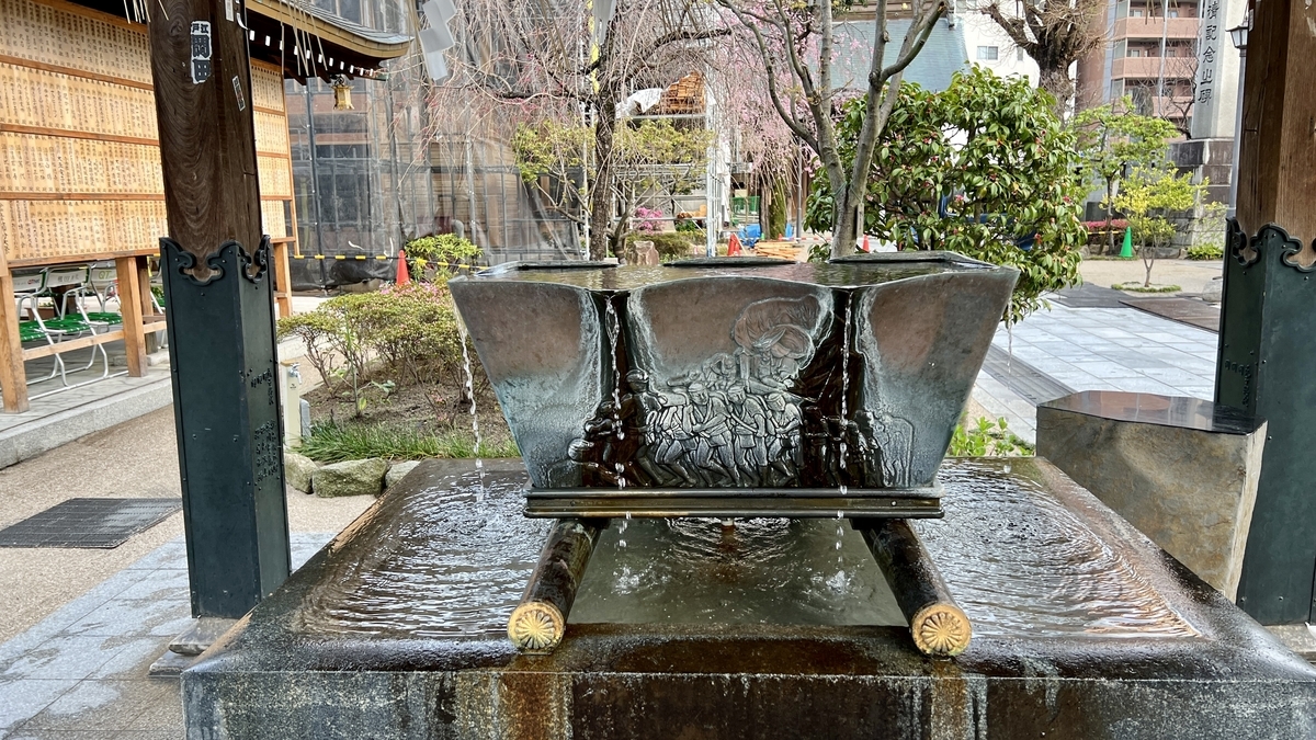 博多祇園山笠の浮彫が入った手水鉢と流れる水