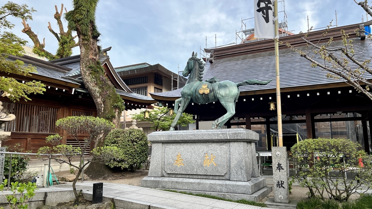 奉献の文字が刻まれた台座に立つ神馬像と社殿
