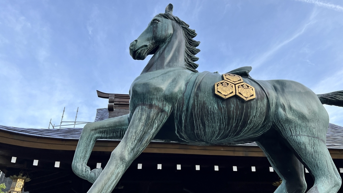 空に映える神馬像の横顔と背に付いた五三桐の紋