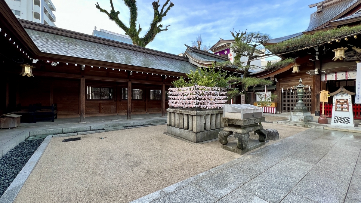 拝殿脇の砂利の中庭とおみくじ掛けの棚