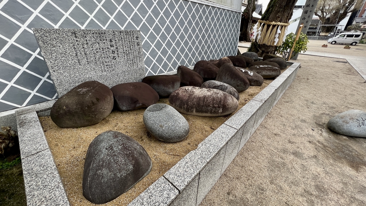 砂地に並べられた博多の関取力石と石碑