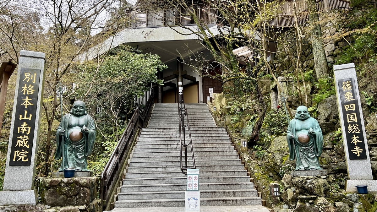 南蔵院の参道入口の石段と左右に並ぶ石柱と布袋像