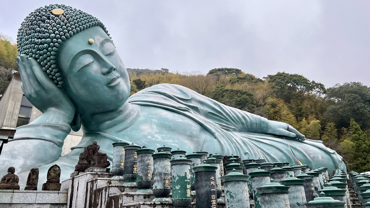 釈迦涅槃像の穏やかな表情と手前に並ぶ供養塔