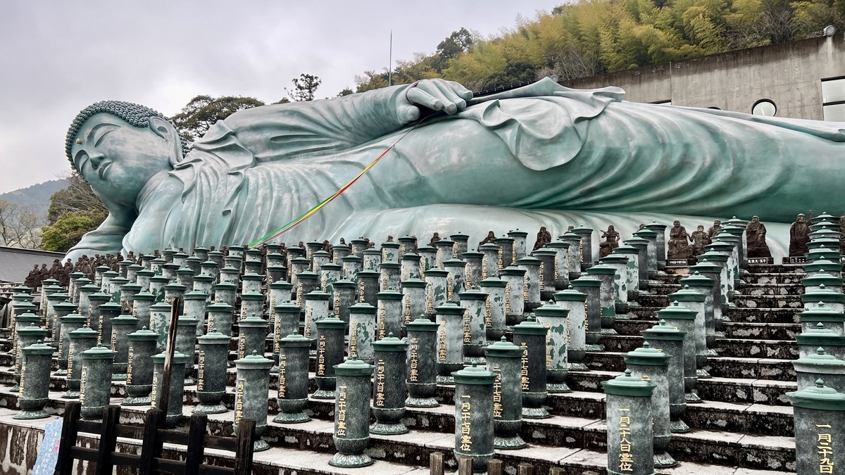 釈迦涅槃像の横姿と段状に並ぶ多数の供養塔