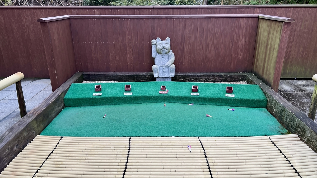 俵投げの的となる枡と招き猫の石像が並ぶ投げ場