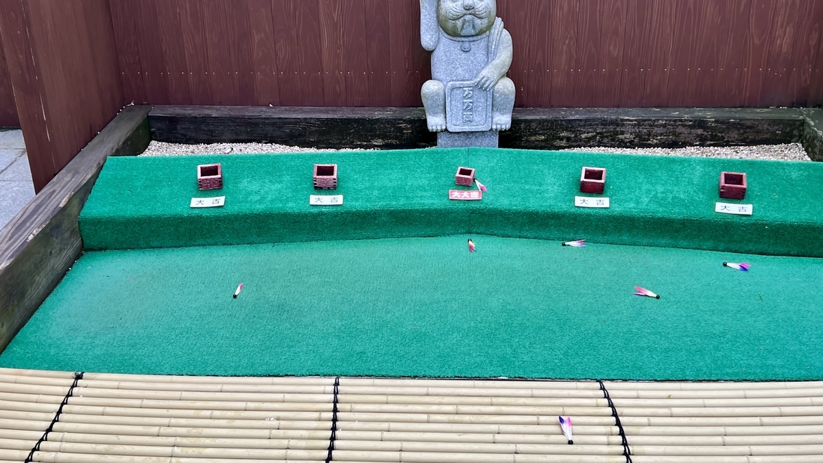 俵投げの枡と大吉札の前に散らばる羽根付き俵