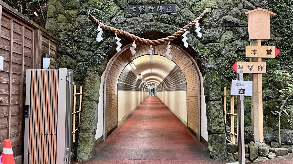 七福神トンネルの入口と岩壁の祠に掛かるしめ縄
