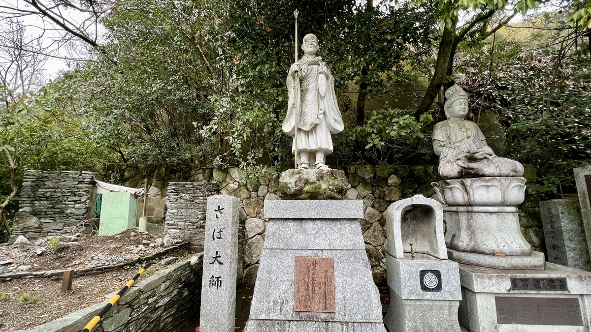 さば大師の石像と横に並ぶ仏像が立つ石段上の広場