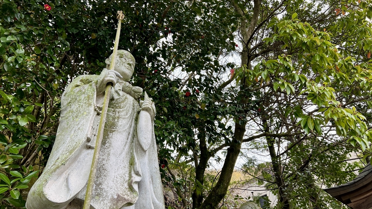 木々の緑に囲まれて立つさば大師像の上半身