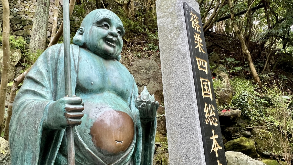 篠栗四国総本寺の石柱の横に立つ布袋像の胸元