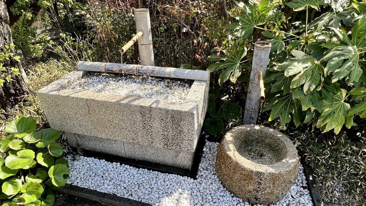 A stone water basin with bamboo ladle and white gravel