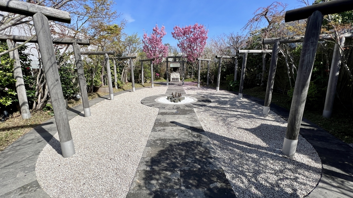 White gravel in a circular plaza with the Seven Lucky Children statue and torii gates