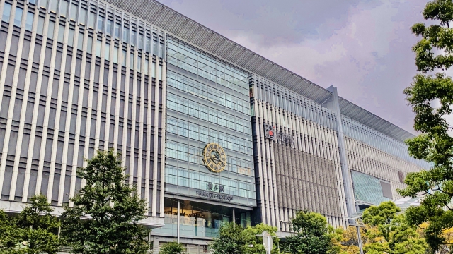 The glass facade of JR Hakata Station building with a large clock visible