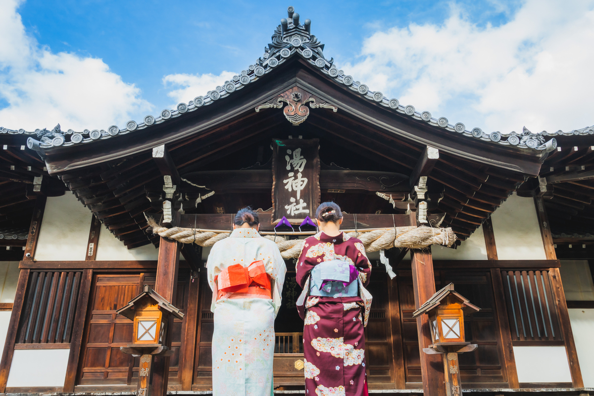 Two women in yukata praying at Yu Jinja Shrine