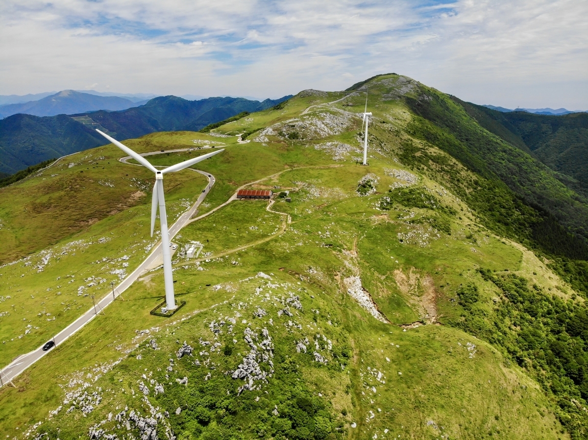 四國喀斯特全景航拍。巨大的風力發電風車和駕車路線。周圍草原延綿