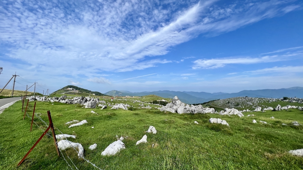 陽光照射的綠色草原中展開的白色岩石與山脈風景