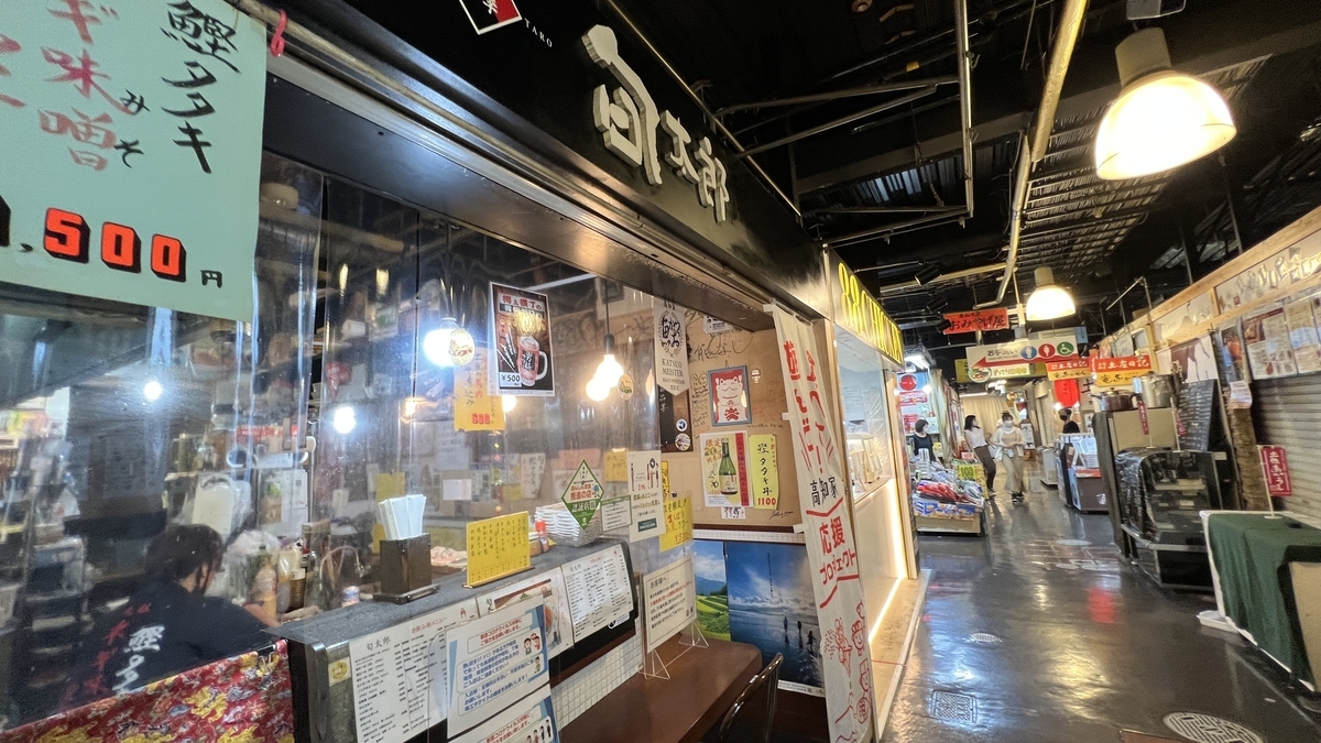 카운터석이 있는 매장과 통로. 메뉴와 제등이 걸려 있어 활기찬 시장 분위기