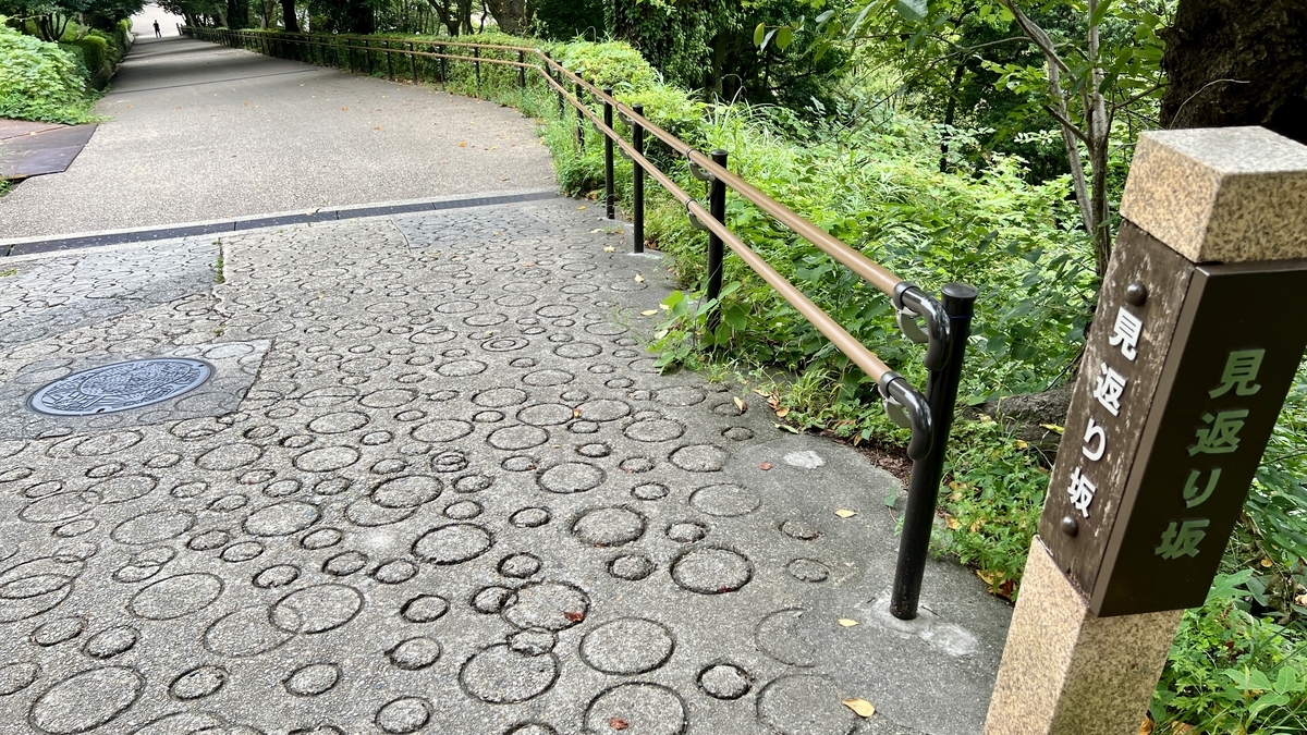Midpoint of Mikaeri-zaka with stone paving and a guidepost. Near the split of the two-tiered slope.