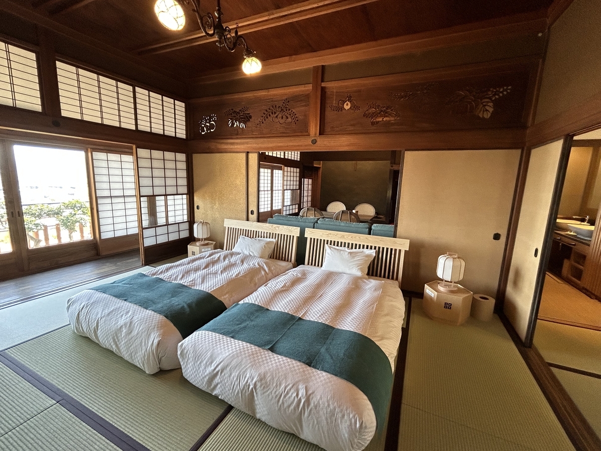 Interior of Enshukaku Villa. Tatami room with neatly arranged futons and soft natural light filtering through shoji screens.