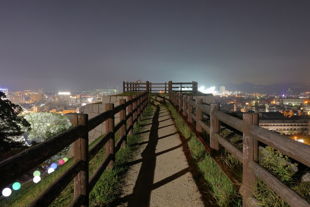 Night view of Marugame City from the castle observatory. A quiet cityscape glowing with lights seen from within the castle.